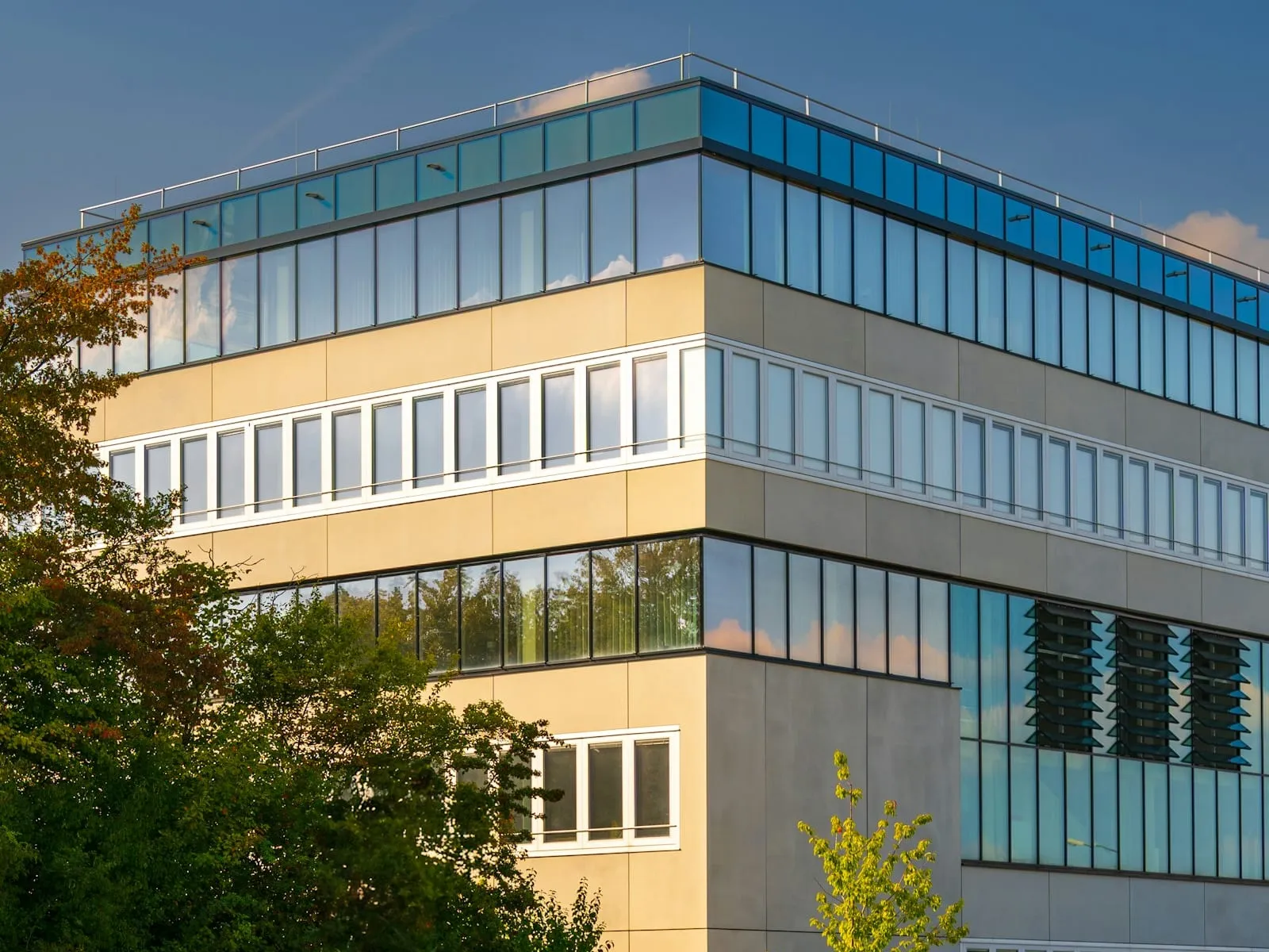 Modernes Bürogebäude mit Fensterbändern und gepflegten Bäumen
